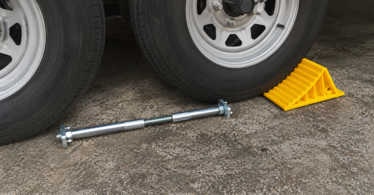 BAL X-Chock wheel stabilizer and Camco yellow wheel chock positioned beside tandem axle RV tires on concrete
